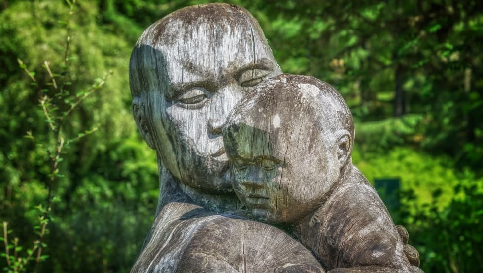 Sculpture en bois d'un parent tenant son enfant contre lui